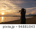 夕暮れ時の猪苗代湖を撮影する女性 94881043