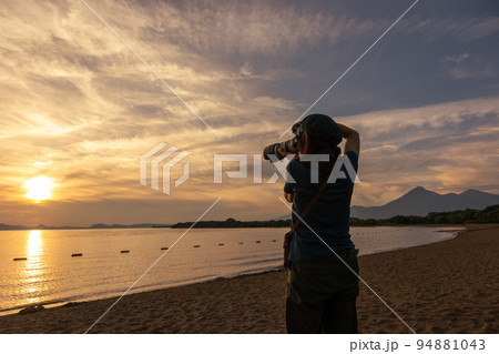 夕暮れ時の猪苗代湖を撮影する女性 94881043