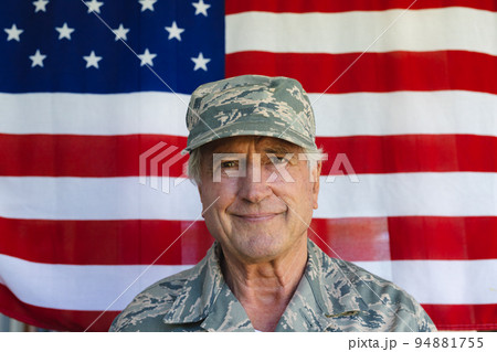 Close-up of confident caucasian army soldier wearing camouflage clothing against flag of america Close-up of confident caucasian army soldier wearing camouflage clothing against flag of america 94881755