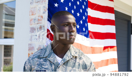 African american mid adult army soldier in camouflage clothing looking away standing against flag African american mid adult army soldier in camouflage clothing looking away standing against flag 94881792