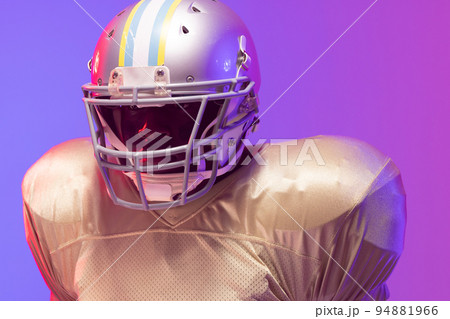 African american male american football player wearing helmet with neon blue and purple lighting African american male american football player wearing helmet with neon blue and purple lighting 94881966