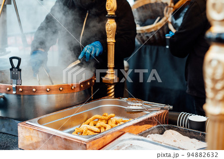 Churreria cooking churros on street market. Churros is a traditional Spain street fast food. Selective focus, copy space. Churreria cooking churros on street market. Churros is a traditional Spain street fast food. Selective focus, copy space. 94882632