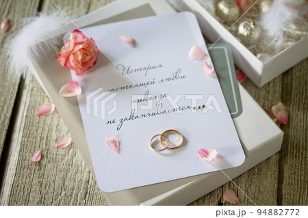 Two Golden Wedding Rings, box of chocolates and a wedding invitation, an inscription that the story of true love never ends. Copy space. 94882772