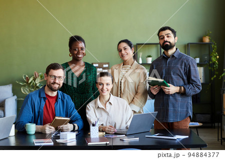 Team of young successful designers gathered by workplace looking at camera Team of young successful designers gathered by workplace looking at camera 94884377