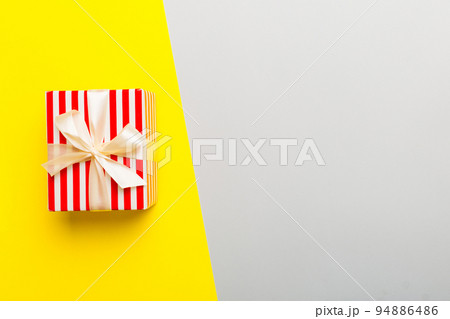 holiday paper present tied yellow ribbon bow top view with copy space. Flat lay holiday background. Birthday or christmas present. Christmas gift box concept with copy space holiday paper present tied yellow ribbon bow top view with copy space. Flat lay holiday background. Birthday or christmas present. Christmas gift box concept with copy space 94886486