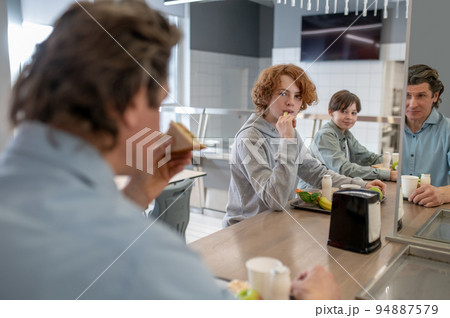 Schoolteacher and two schoolboys eating lunch together Schoolteacher and two schoolboys eating lunch together 94887579