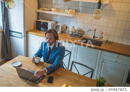 Man in blue suit having a vieo call and looking contented 94887623