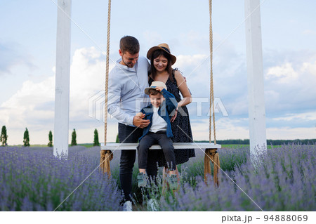Happy family with son on swing in lavender field Happy family with son on swing in lavender field 94888069