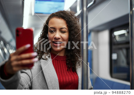 smiling woman taking a selfie while standing on a subway train . smiling woman taking a selfie while standing on a subway train . 94888270
