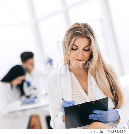 scientist make notes to the clipboard in the clinical laborator 94888459