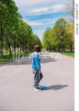 Young stylish woman wears sunglasses walks on the street with a skateboard Young stylish woman wears sunglasses walks on the street with a skateboard 94889739