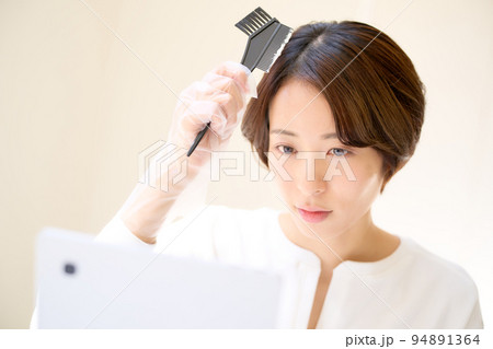 鏡を見ながら自分の髪を染める若い女性　セルフヘアカラー　イメージ 94891364