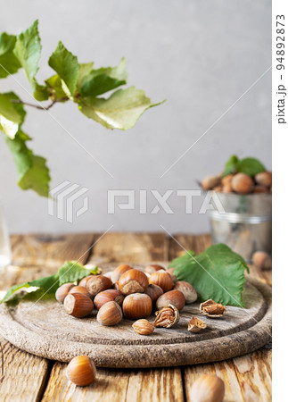 Hazelnuts on wooden rustic cutting board and table with hazelnut tree branch Hazelnuts on wooden rustic cutting board and table with hazelnut tree branch 94892873