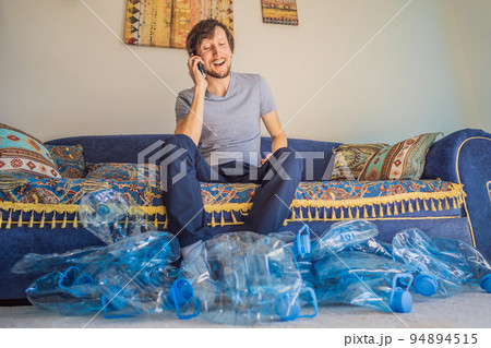 Young caucasian man hamong empty plastic bottles to recycle with sad expression 94894515