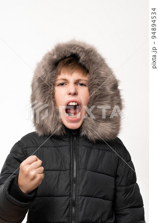 A boy in a winter jacket with a hood on a white background. A boy in a winter jacket with a hood on a white background. 94894534