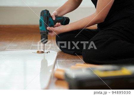 Close-up of young woman making repair with drill in the room 94895030