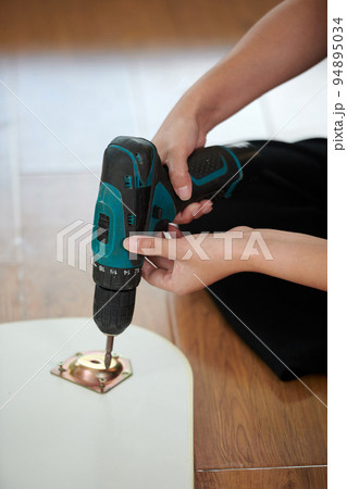 Close-up of young woman using screwdriver to make wooden detail at home Close-up of young woman using screwdriver to make wooden detail at home 94895034