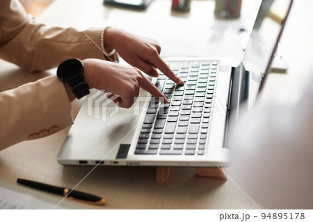 Close-up of young businesswoman typing on keyboard of laptop at table 94895178