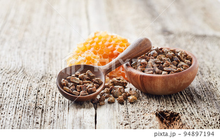 Propolis granules with honeycomb on wooden background Propolis granules with honeycomb on wooden background 94897194
