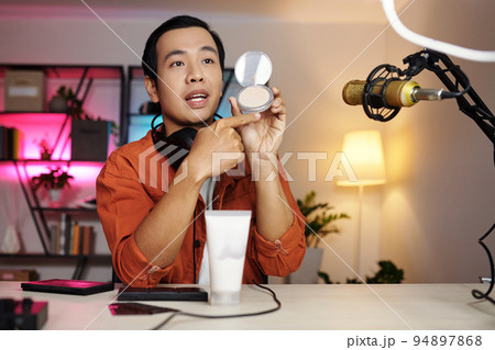 Horizontal medium portrait of modern Asian male beauty blogger making review or advertisment for new cosmetic products 94897868