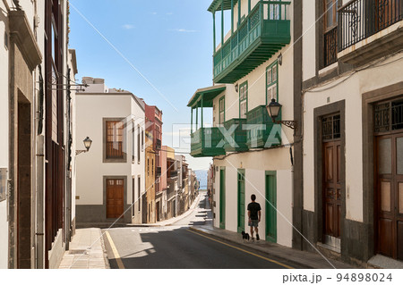 Las Palmas, Gran Canaria. Man walking his dog in an old street leading to the ocean. Las Palmas, Gran Canaria. Man walking his dog in an old street leading to the ocean. 94898024