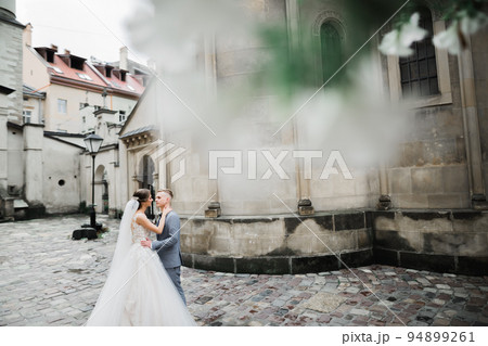 Beautiful bride and groom embracing and kissing on their wedding day outdoors 94899261