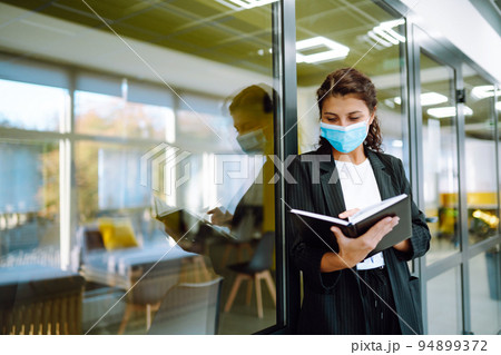 Portrait of young man with face mask back at work in office after lockdown. Portrait of young man with face mask back at work in office after lockdown. 94899372