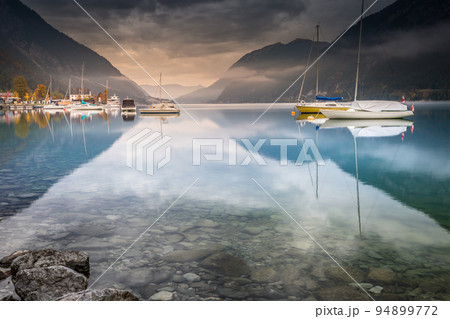 Sailboats in Achensee lake near Innsbruck at peaceful dawn, Tyrol alps, Austria Sailboats in Achensee lake near Innsbruck at peaceful dawn, Tyrol alps, Austria 94899772