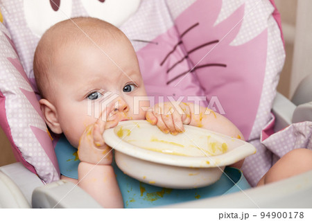 baby girl eating with spoon in kitchen baby girl eating with spoon in kitchen 94900178