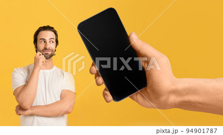 Pensive millennial european man look at huge smartphone with blank screen in hand 94901787