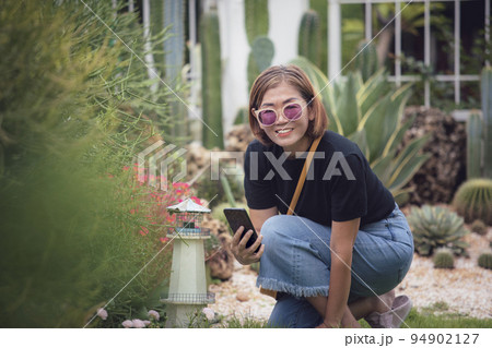 beautiful asian woman holding smart phone toothy smiling in home garden beautiful asian woman holding smart phone toothy smiling in home garden 94902127