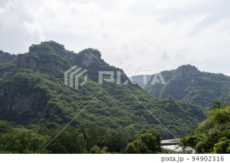 dirty river seen through the huentitan ravine in guadalajara, green vegetation, trees, plants and mountains, mexico 94902316