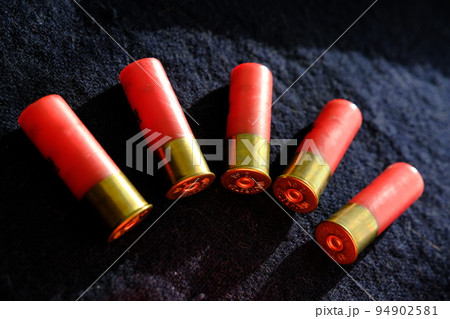 Shotgun shells on a black surface. Ammunition for 12 gauge smoothbore weapons. Hunting ammunition. Dark background. Shotgun shells on a black surface. Ammunition for 12 gauge smoothbore weapons. Hunting ammunition. Dark background. 94902581