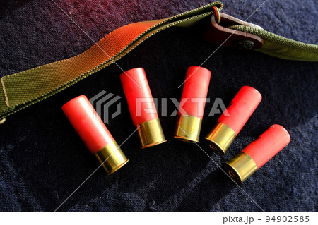 Shotgun shells on a black surface. Ammunition for 12 gauge smoothbore weapons. Hunting ammunition. Dark background. Shotgun shells on a black surface. Ammunition for 12 gauge smoothbore weapons. Hunting ammunition. Dark background. 94902585