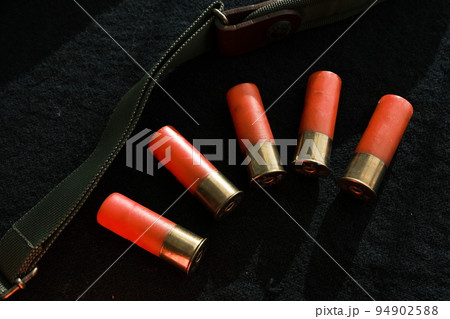 Shotgun shells on a black surface. Ammunition for 12 gauge smoothbore weapons. Hunting ammunition. Dark background. Shotgun shells on a black surface. Ammunition for 12 gauge smoothbore weapons. Hunting ammunition. Dark background. 94902588