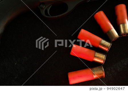 Trigger of a rifle on black background with red lightning with Shotgun shells on a black surface. Ammunition for 12 gauge smoothbore weapons. Hunting ammunition. Dark background. 94902647