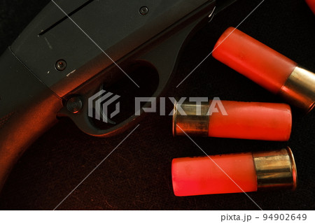 Trigger of a rifle on black background with red lightning with Shotgun shells on a black surface. Ammunition for 12 gauge smoothbore weapons. Hunting ammunition. Dark background. 94902649