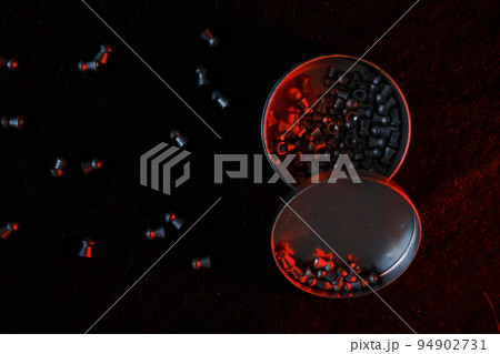 air gun pellets on darck cloth background with red light for illumination 94902731