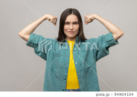 I am strong and independent. Confident proud woman showing biceps, expressing power ambitions to become successful, feminism concept, female rights. Indoor studio shot isolated on gray background. 94904104