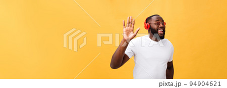 Young African American man wearing headphone and enjoy music over yellow gold Background Young African American man wearing headphone and enjoy music over yellow gold Background 94904621