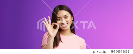 Cute smiling asian girl approve good plan, show okay ok sign, tilt head lovely grinning, satisfied perfect quality product, give positive feedback, accept choice, stand purple background 94904631