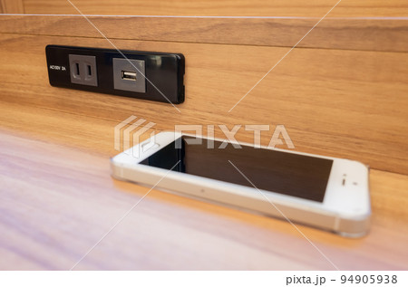 【日本】コンビニのコンセントがあるテーブル上に置かれたスマートフォン 94905938