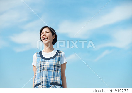 青空の下で園児を呼ぶ保育士 94910275