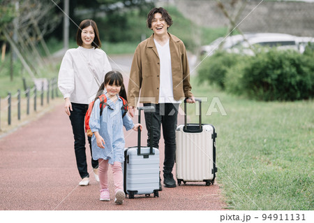 楽しい旅行・スーツケースを引く笑顔の家族・子育てイメージ 94911131
