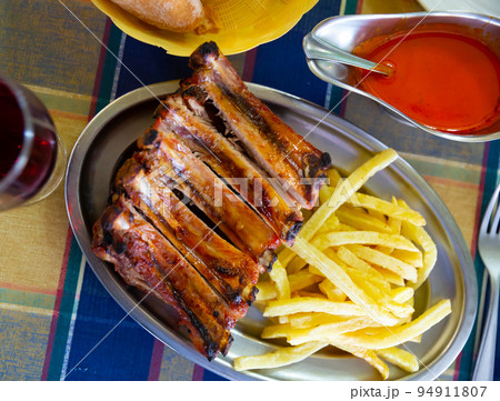 Pork barbeque ribs with french fries served with ketchup Pork barbeque ribs with french fries served with ketchup 94911807