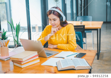 young student wearing headphones studies online, distance learning, and keeps up to date on the global coronavirus pandemic. 94912258