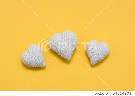 Handmade for Valentine's Day. Knitted white hearts on a yellow background Handmade for Valentine's Day. Knitted white hearts on a yellow background 94914303