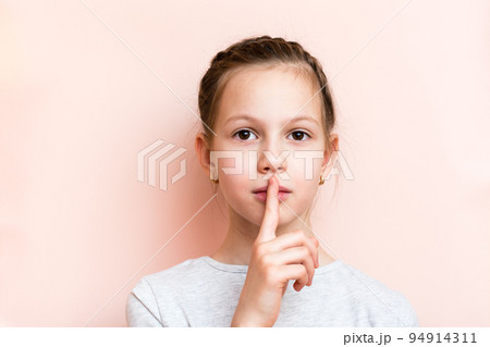 Surprised girl holds her finger in front of her lips. Call for silence 94914311