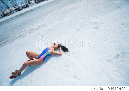 Caucasian woman in a swimsuit sunbathes on the snow in winter. 94915962