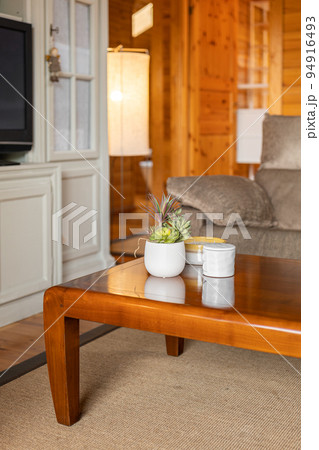 Wooden tea table with candles and a white vase with plants in the interior of the cottage living room 94916493